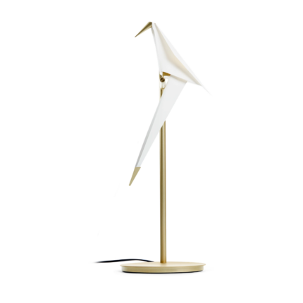 PERCH TABLE LIGHT BY UMUT YAMAC with single white origami paper bird perched on slim brass stem and round gold base, swivel design