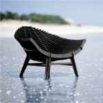 BLACK ARMCHAIR BY RACHEL & BENOIT CONVERS— wide seat formed from closely spaced parallel horizontal slats creating a ribbed manta ray silhouette, on four angled legs with cross-bracing