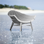 WHITE ARMCHAIR BY RACHEL & BENOIT CONVERS— wide seat photographed from the rear three-quarter angle standing in shallow coastal water
