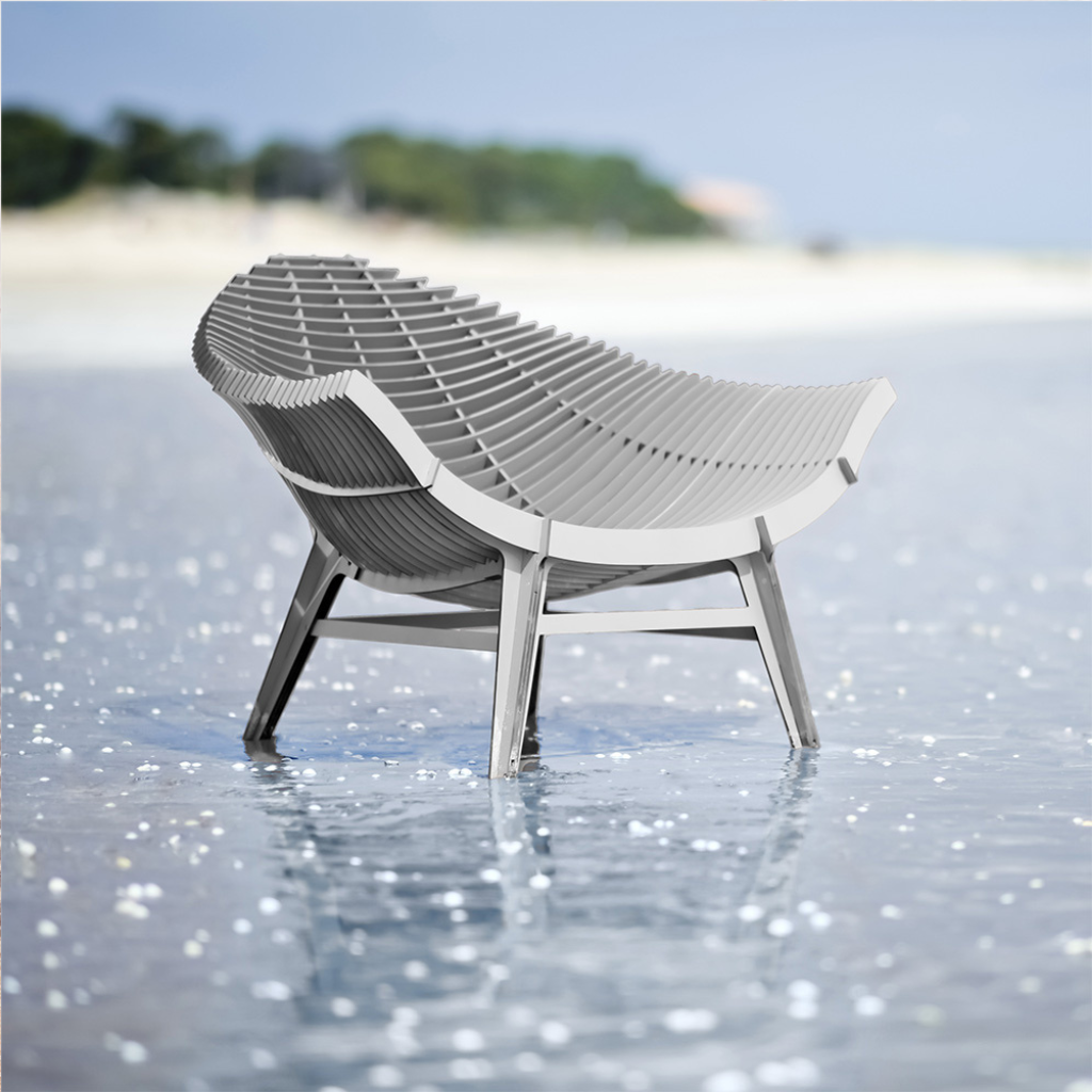 WHITE ARMCHAIR BY RACHEL & BENOIT CONVERS— wide seat photographed from the rear three-quarter angle standing in shallow coastal water WHITE ARMCHAIR BY RACHEL & BENOIT CONVERS— wide seat photographed from the rear three-quarter angle standing in shallow coastal water