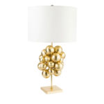 PLUTONE TABLE LAMP with cluster of polished gold spheres on a slim stem and square base topped with a wide ivory drum shade