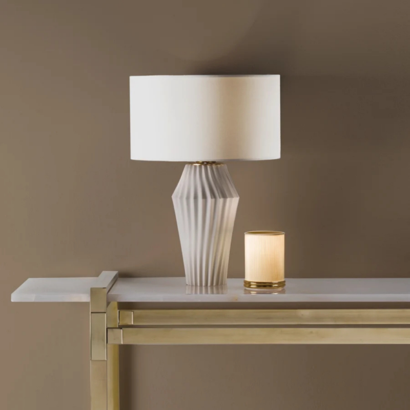 VERTIGO TABLE LAMP MATT WHITE with geometric diagonal ribbed faceted base and white drum shade on gold console, made in Italy